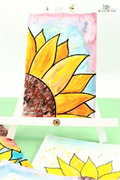 an easel with two paintings on it and one has a sunflower painted on it