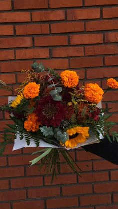 a bouquet of flowers sitting on top of a piece of paper next to a brick wall