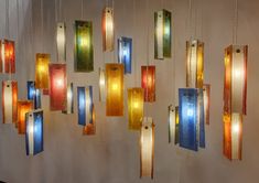 a group of multicolored lights hanging from a wall next to a white wall