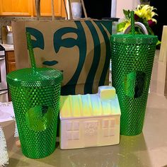 three green glass cups sitting on top of a counter next to a shopping bag and other items