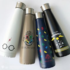 four harry potter water bottles lined up on a white surface with the words hogwart printed on them