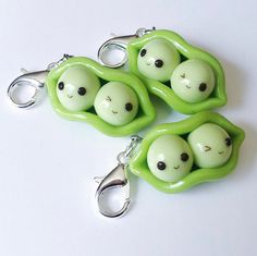 three peas with faces on them sitting next to each other and one is holding a pair of scissors