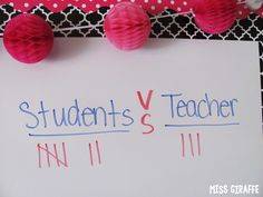 a sign that says students vs teacher next to some paper balls on a black and white tablecloth