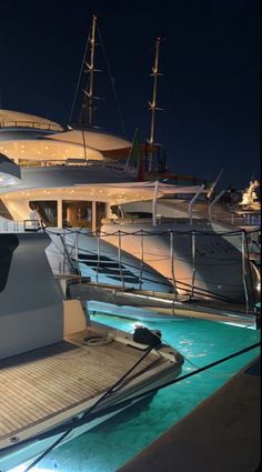 several yachts are docked at night with lights on the deck and in the water