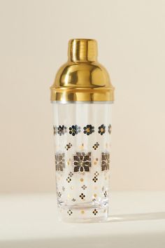 a shot glass sitting on top of a counter next to a gold lid and metal spigot