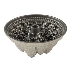 a metal bowl that is sitting on a white table top, with an intricate design in the center