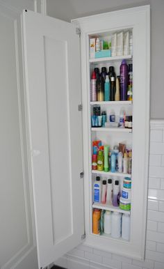 an open medicine cabinet in the corner of a bathroom with lots of bottles and shampoos