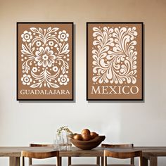 two wall hangings above a wooden table with fruit on it in front of them