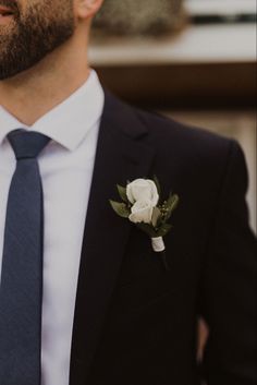 a man wearing a suit and tie with a boutonniere on his lapel