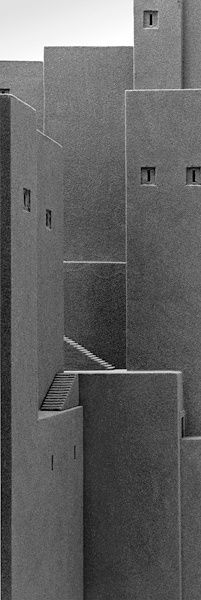 a black and white photo of an abstract building made out of concrete blocks with the door open