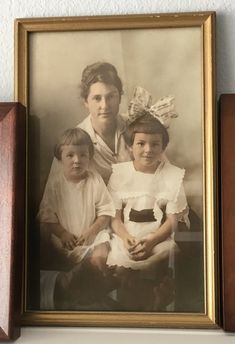 an old photo of two children and one adult sitting next to each other on a shelf