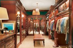 a walk - in closet with lots of clothes on hangers and drawers, along with a bench