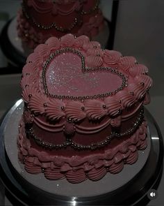 a pink heart shaped cake sitting on top of a silver platter next to other cakes