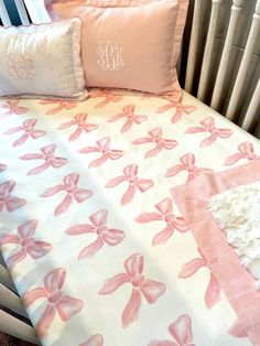 a crib bed with pink bows and monogrammed pillows