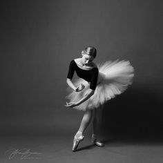 a young ballerina is posing in black and white