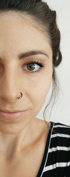 a woman with some piercings on her nose looking at the camera while wearing a black and white striped shirt