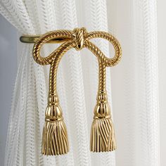 a curtain with two tassels hanging from it's side, in front of white curtains