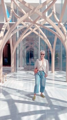 a woman standing in front of a building with large wooden beams on it's sides