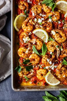 a pan filled with shrimp and garnish next to lemon wedges on top of a table