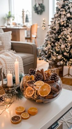 a table topped with oranges and cookies on top of a white counter next to a christmas tree