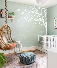 a baby's room with a swing chair and tree decal on the wall