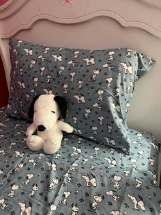 a stuffed dog sitting on top of a bed with blue sheets and pillowcases