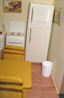 small kitchen with white appliances and yellow chairs