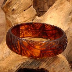 This vintage Bakelite bracelet is a beautiful piece of retro jewelry measuring 8 inches in length inside diameter. The tortoise shell brown and golden yellow color of the Bakelite material makes it a versatile piece that can be worn with a variety of outfits. The curvy, swaying leaf design is expertly carved and adds a touch of elegance.  The bracelet is a perfect gift for any occasion, whether it's Mother's Day, Christmas, graduation, anniversary, or birthday.  Its unique style and theme of art, flowers & plants make it a one-of-a-kind piece that is sure to impress.  This bangle is a must-have for any fashion jewelry lover and is a great addition to any retro jewelry collection. Excellent vintage conditon with very minimal scratching if any. Tested Bakelite 21.00 mm wide x 7.11 mm thick Bakelite Bracelets, Bakelite Jewelry, Golden Yellow Color, Vintage Bakelite, Retro Jewelry, Art Flowers, Of Outfits, Flowers Plants, 1950s Vintage