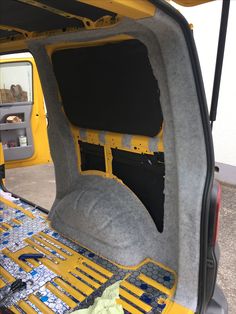 the back end of a yellow vehicle with its door open and seats folded up in place