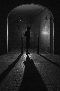 a person standing in the dark with their shadow on the ground