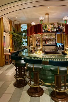 A view of the Art Deco interior design style horseshoe bar with barstools, green granite and red velvet curtains in the lobby of the Georgian Hotel in Santa Monica, California. Emerald Quartzite, Horseshoe Bar, Quartzite Counters, Red Velvet Curtains