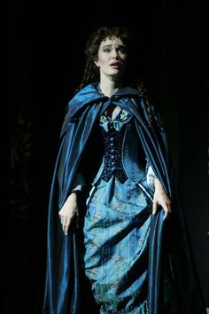 a woman in a blue dress and cape