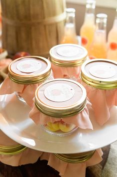 there are many jars on the plate with pink ribbons around them and some orange juice in the background