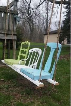 two chairs sitting on swings in the grass