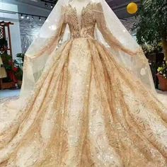 a wedding dress on display in a room with lights and flowers behind it, the veil is