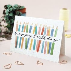 a birthday card with colorful candles on it and some scissors next to it, along with other crafting supplies