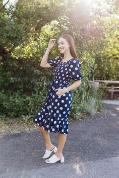 The Royal Midi dress is a must-have addition to your wardrobe. With its navy color and big white polka dots, you'll make a statement wherever you go. The smocked bodice and short puff sleeves add a playful touch, while the square neck and pockets add functionality. The tiered design creates a flattering silhouette. Perfect for any occasion. Fits true to size. Model is wearing a small and is 5'6". Plus model is wearing an XL and is 5'7". Size Chart Length Bust Waist S 39" 30" 26" M 39.5" 32" 28" Teen Dress, Tiered Dresses, Spring Fits, Navy Color, White Outfits, White Polka Dot, Floral Maxi Dress, Jeans Dress, Short Sets