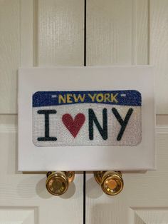 a new york i love ny sign hanging on the front door with two gold knobs