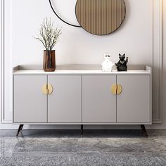 a white sideboard with two vases and a black cat on it in front of a round mirror