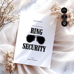 a card with the words ring security on it next to some flowers and white fabric