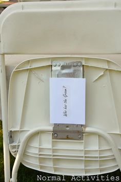 a piece of paper is attached to the back of a white chair with metal legs