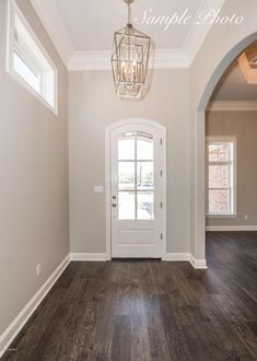 an empty entryway with a white door and wood flooring in the middle of it