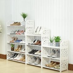 a white shelf filled with lots of shoes next to a vase and potted plant