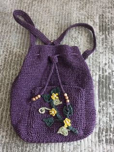 a crocheted purple purse with flowers on it