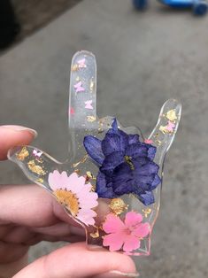 a person holding up a plastic hand with flowers painted on the palm and gold flakes