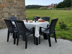 the table is set for four outside by the stone wall and grassy field in the background