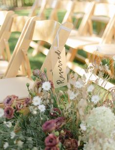 an arrangement of flowers and wooden chairs at a wedding