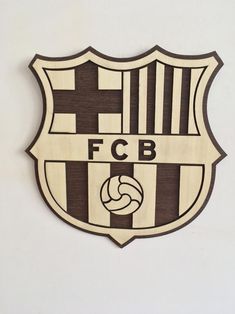 a wooden sign that says f c b on the side of a white wall with black and brown stripes