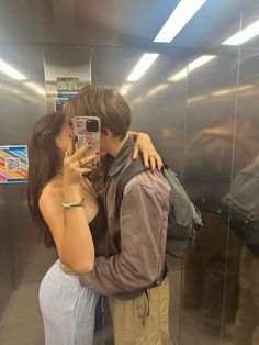 a man and woman taking a selfie in an elevator with their cell phone up to their ear