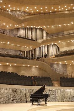 a grand piano sits in the middle of an empty concert hall with people sitting on the seats